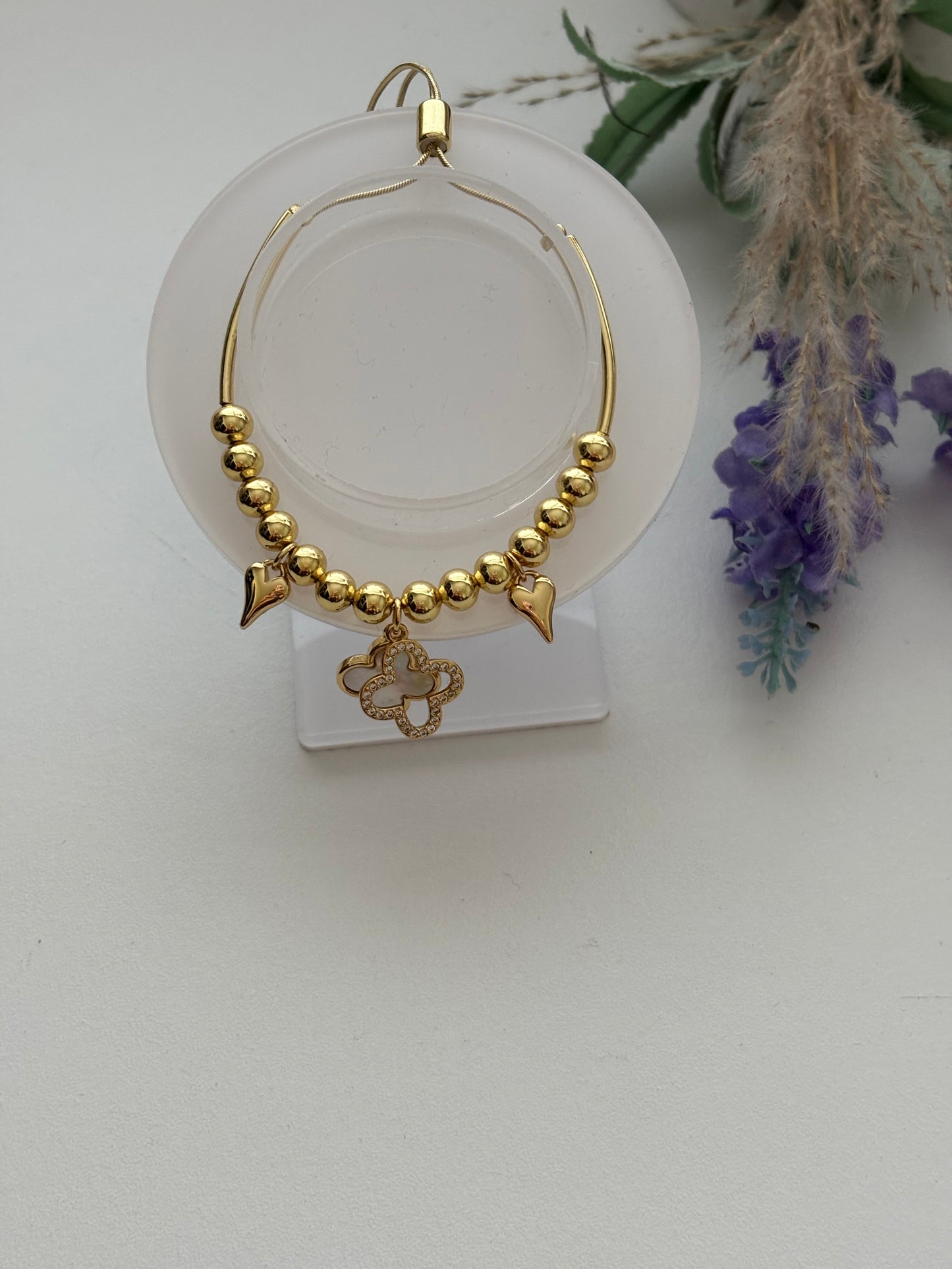 Pulsera dorada con dijes de corazón y trébol