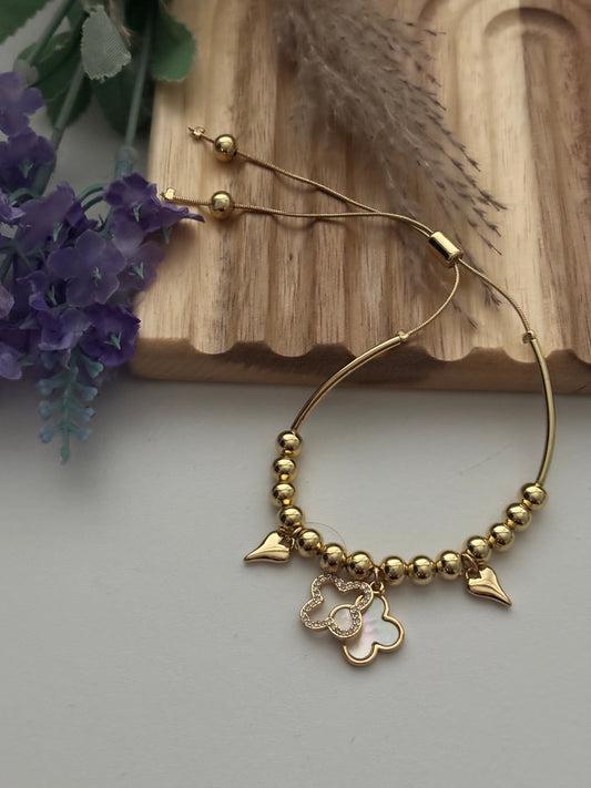 Pulsera dorada con dijes de corazón y trébol